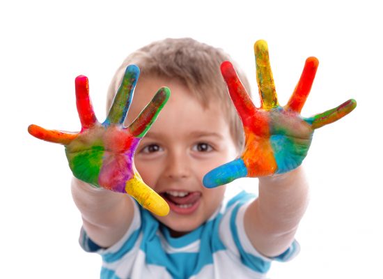 Creative education Boy with hands painted in colorful paints ready to make hand prints
